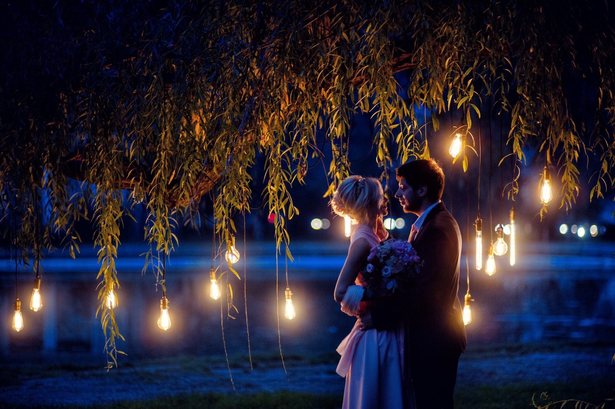 Een verlichte boom met daarvoor een dansend stel tijdens hun buiten bruiloft