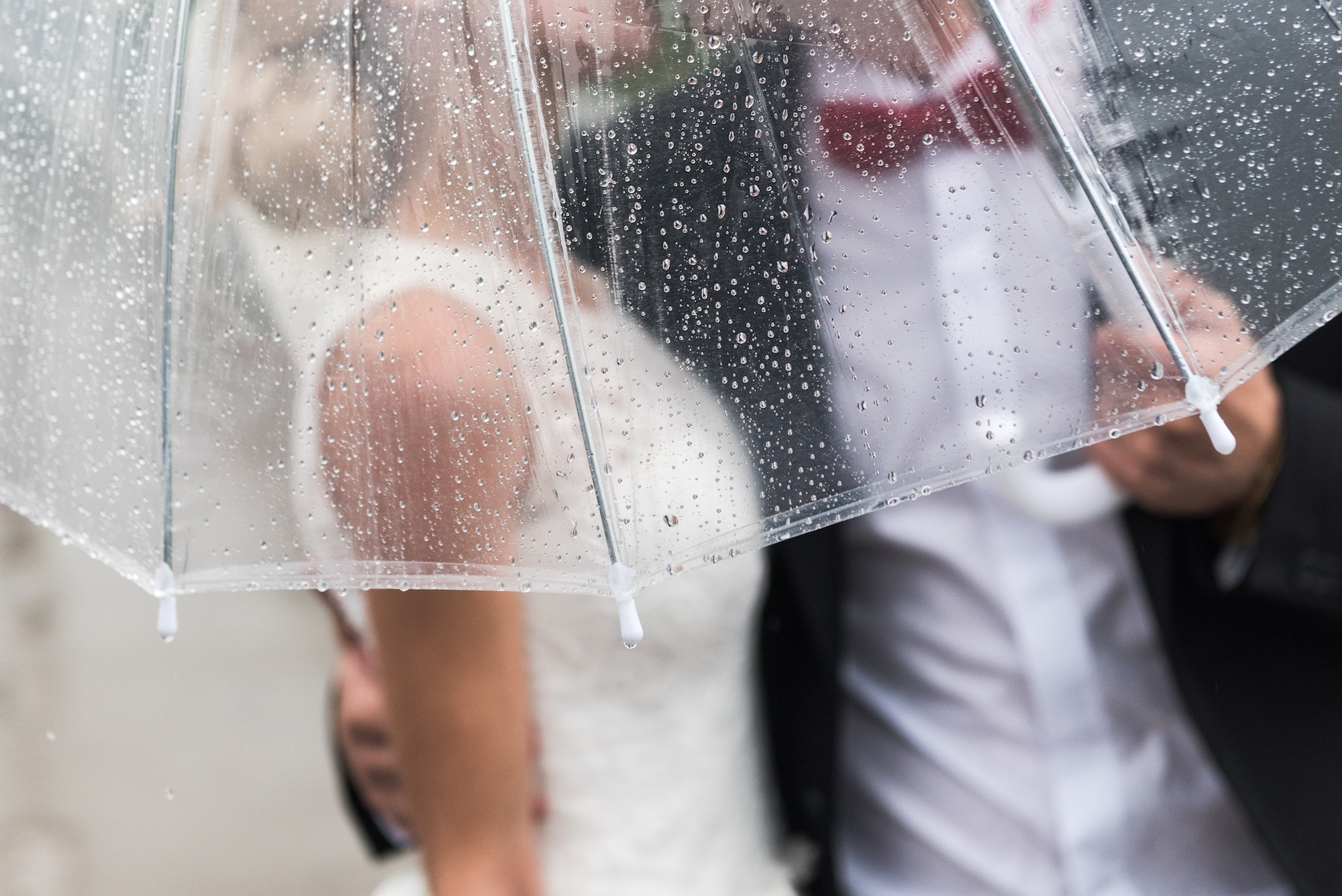 Koppel met paraplu in de regen omdat ze buiten trouwen